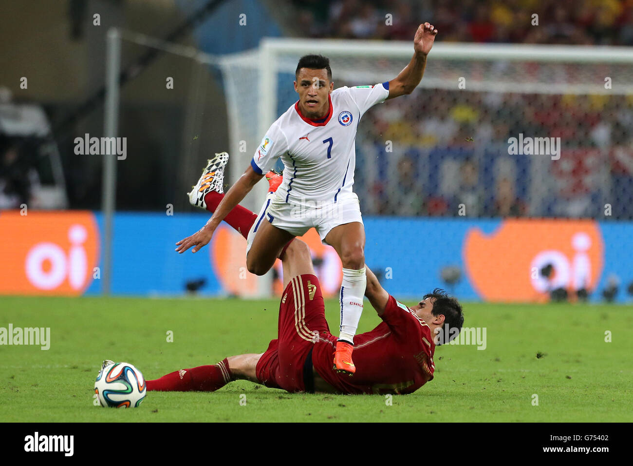 Soccer - FIFA World Cup 2014 - Group B - Spain v Chile - Maracana. Chile's Alexis Sanchez skips a challenge from Spain's Javi Martinez (floor) Stock Photo