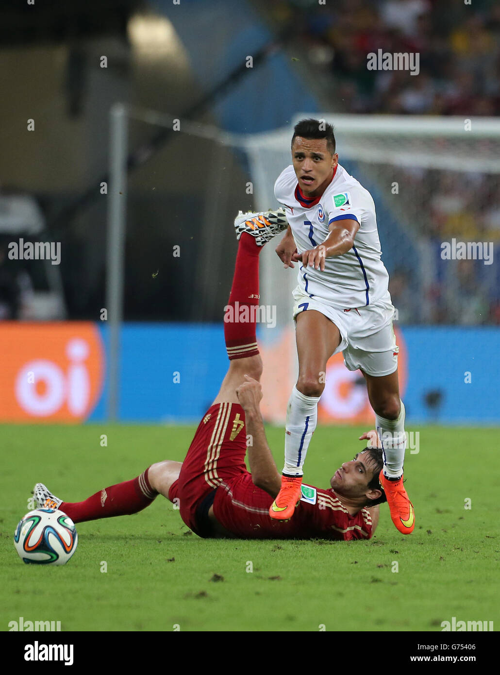 Soccer - FIFA World Cup 2014 - Group B - Spain v Chile - Maracana. Chile's Alexis Sanchez skips a challenge from Spain's Javi Martinez (floor) Stock Photo