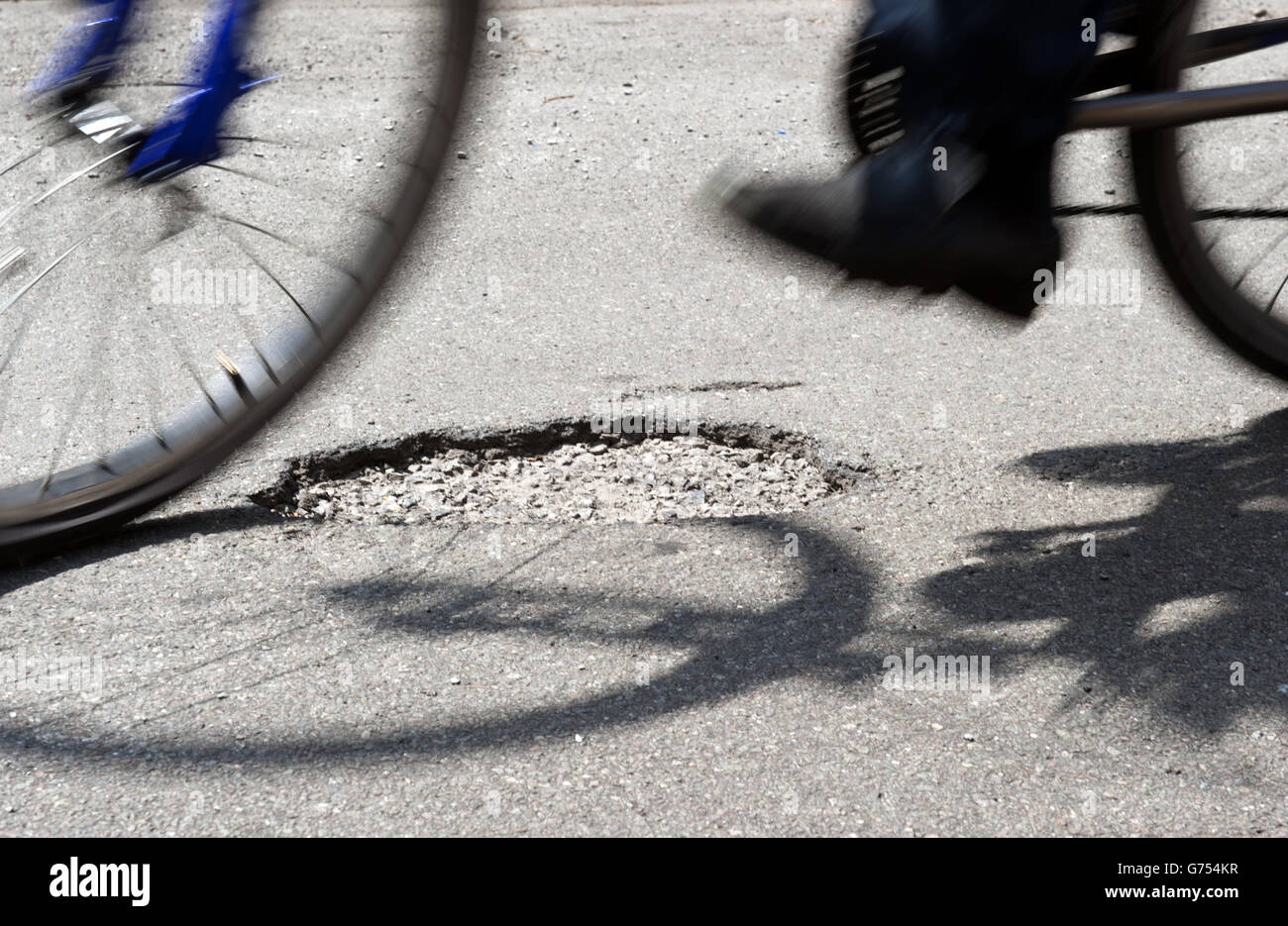 Pothole Stock. A cyclist rides over a pothole on a road in Kimberley, Nottingham Stock Photo