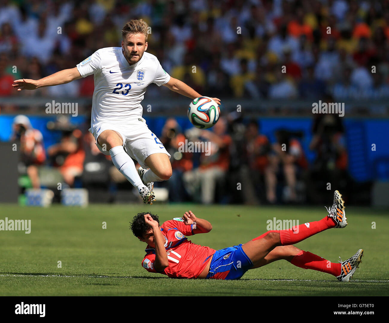 England's Luke Shaw hurdles a challenge from Costa Rica's Yeltsin Tejeda (floor) as they battle for the ball during the FIFA World Cup, Group D match at the Estadio Mineirao, Belo Horizonte, Brazil. Stock Photo
