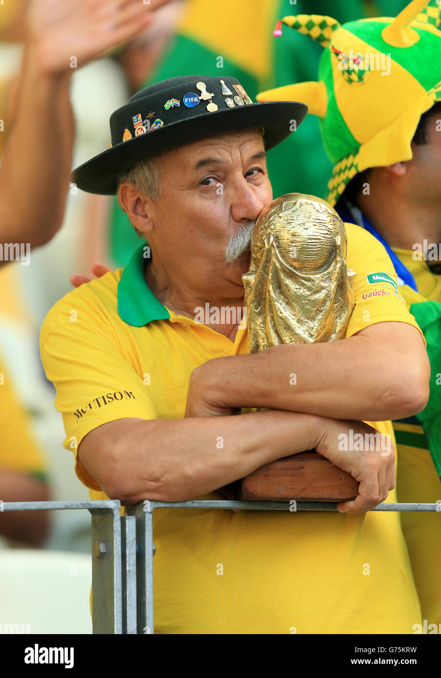 A Brazil fan kisses a replica of the World Cup trophy in the stands before the quarter final match at the Estadio Castelao, Fortaleza. Stock Photo