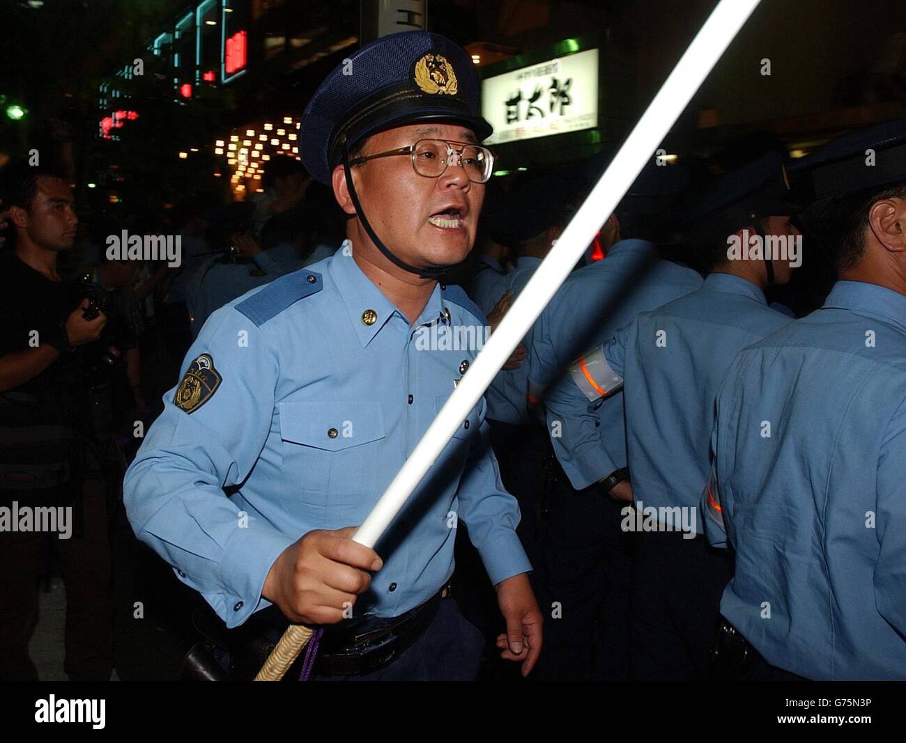 A Japanese policeman with a stick like restrainer in the Roppongi area of Tokyo, Japan after fans celebrated Englands 1-0 win against Argentina. Stock Photo