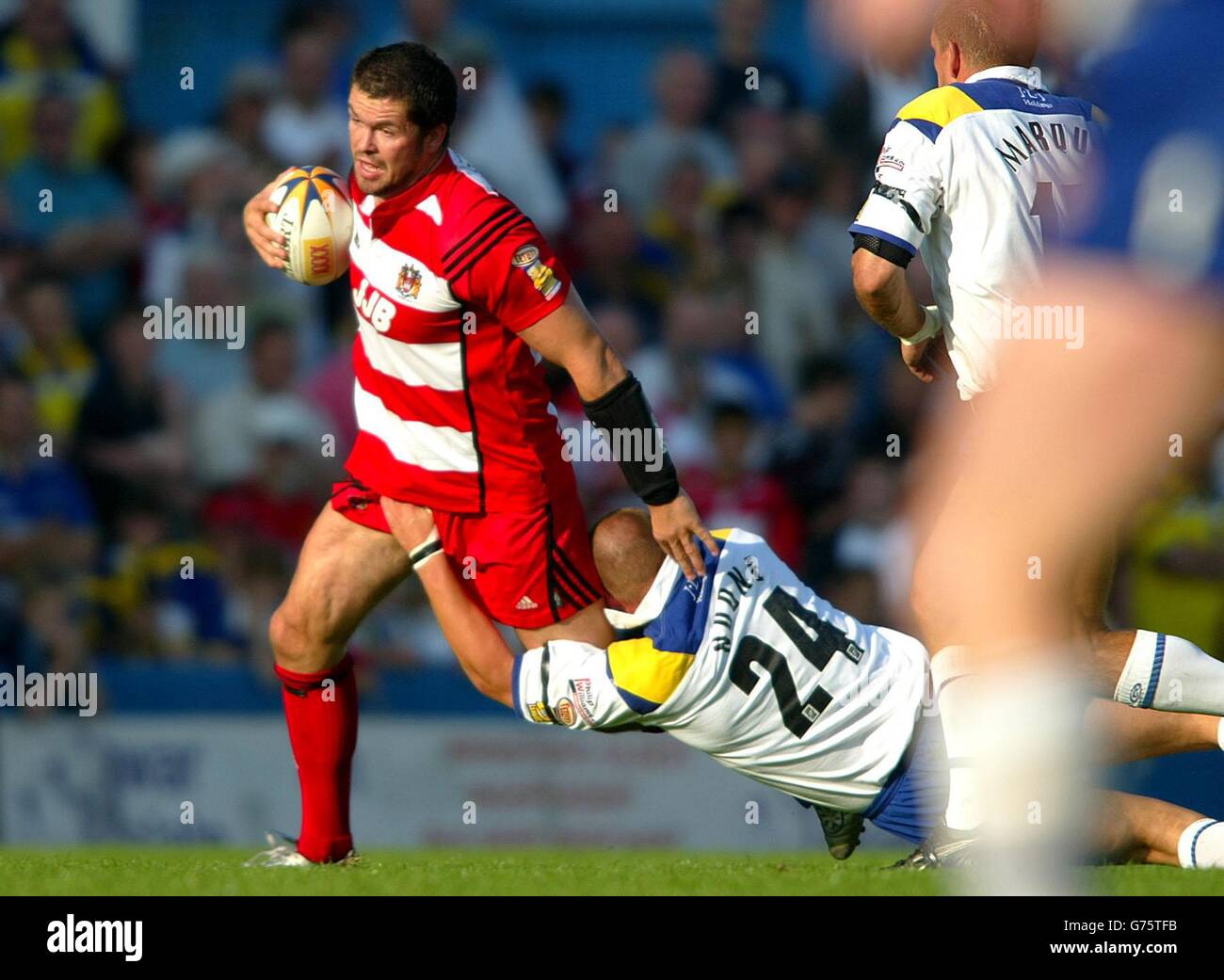 Wigan's Andy Farrell holds off a diving tackle from Warrington's Paul Noone during the Tetley's Bitter Super League match at Wilderspool stadium, Warrington. Stock Photo