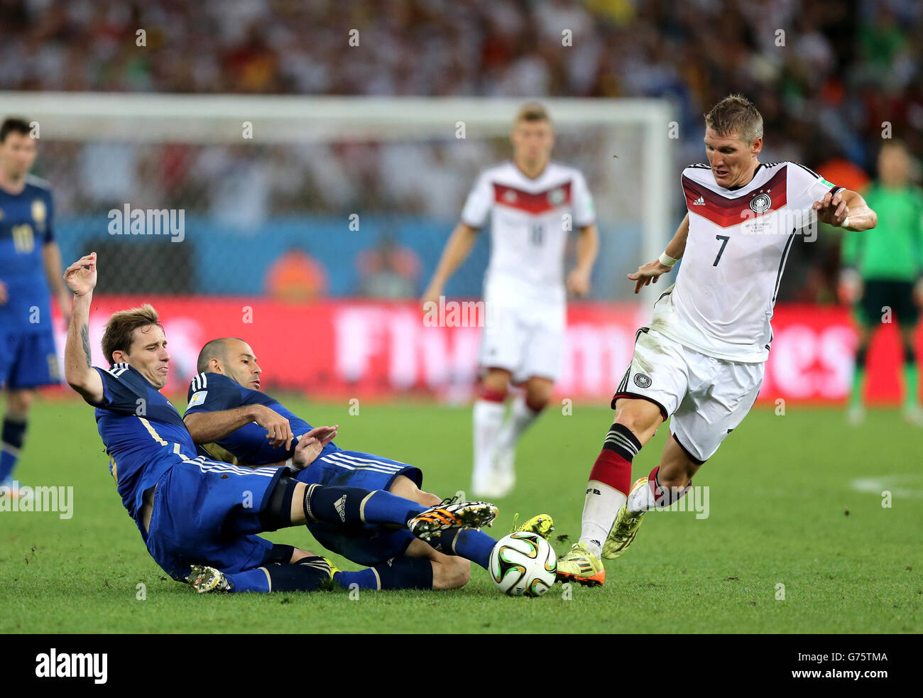 Germany's Bastian Schweinsteiger (right) is tackled by Argentina's Lucas Biglia (left) and Javier Mascherano Stock Photo