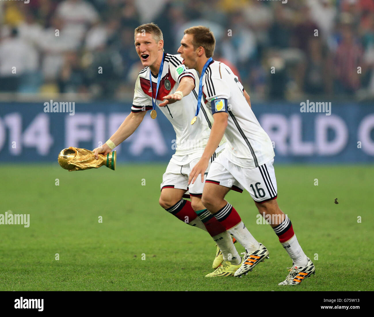 Germany's Bastian Schweinsteiger (left) and Philipp Lahm and the World Cup trophy after the FIFA World Cup Final at the Estadio do Maracana, Rio de Janerio, Brazil. Stock Photo
