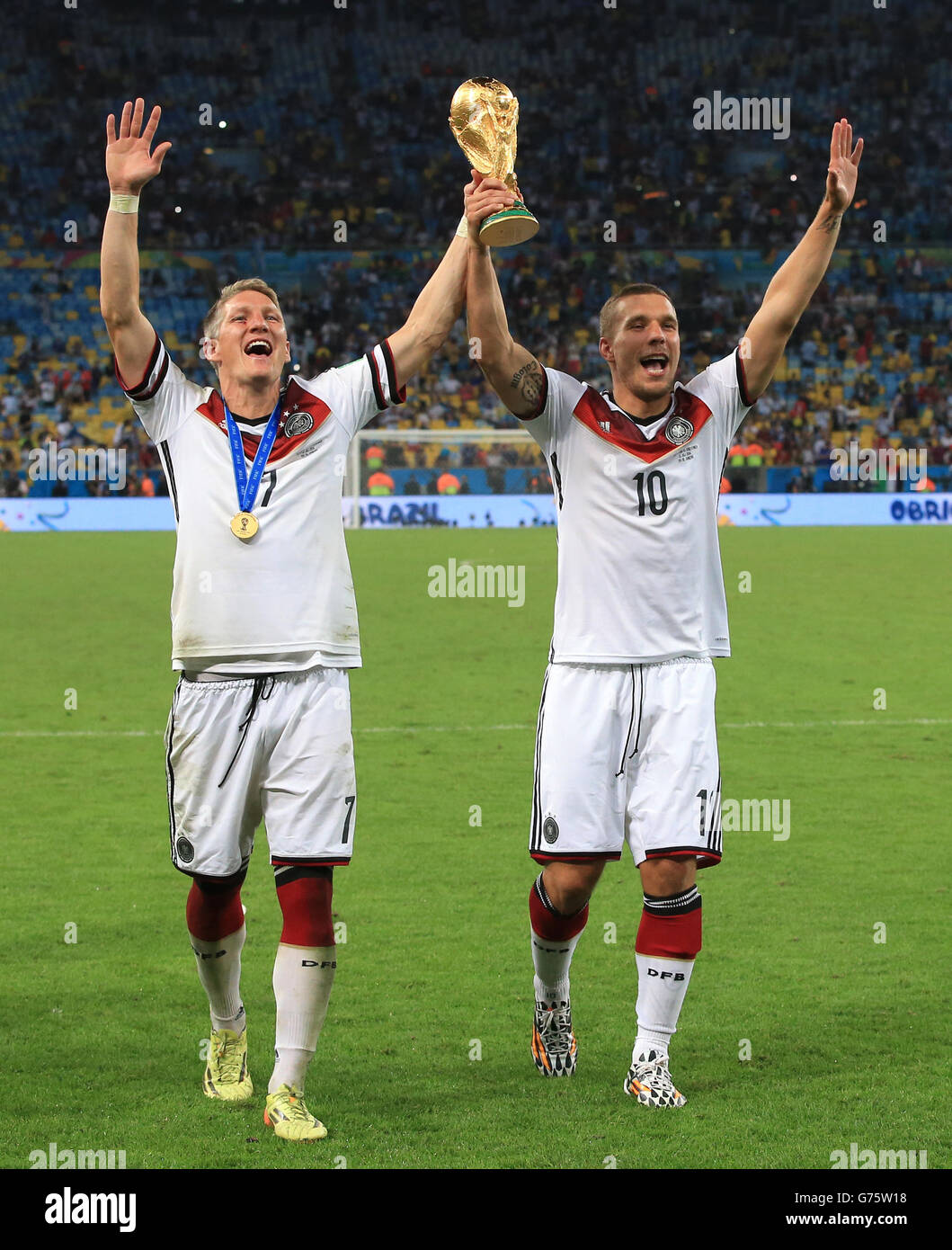 Germany's Bastian Schweinsteiger (left) and Lukas Podolski celebrate on the pitch with the FIFA World Cup 2014 Trophy Stock Photo