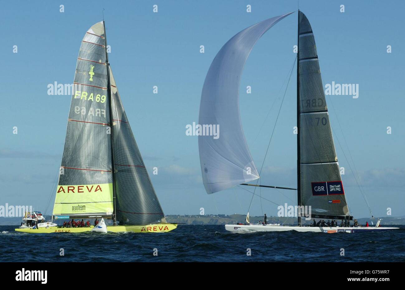 Britain's America's Cup team GBR Challenge (right) cruises across the finish line in the Hauraki Gulf off Auckland, New Zealand as the French yacht Le Defi Areva perfoms a penalty turn on the line. Winning by just 13 seconds, it was GBR's first point in three races. Stock Photo