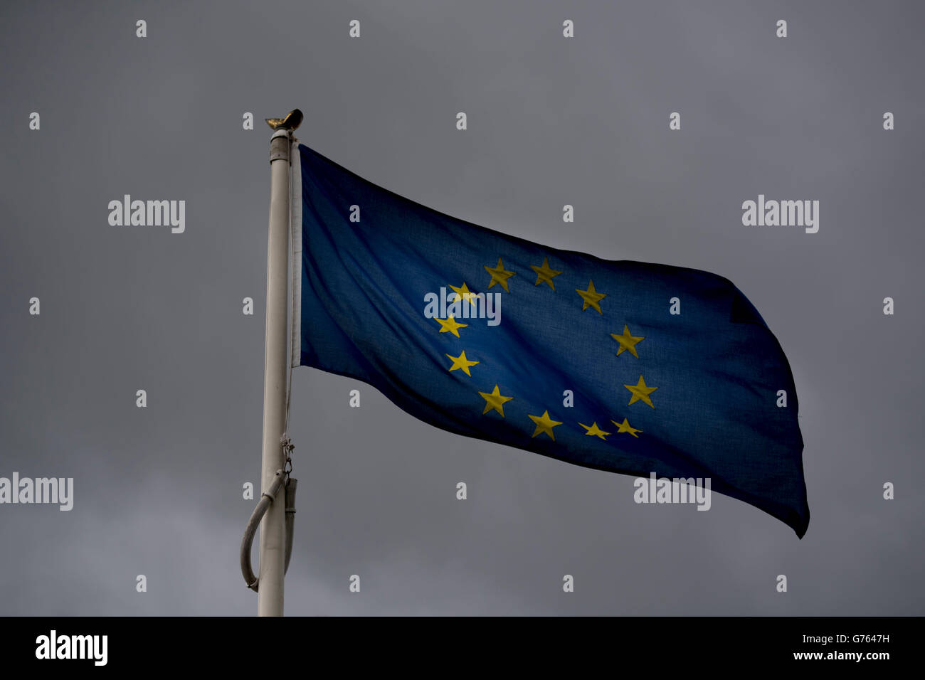 European Union (EU) flag blowing in the wind with dark storm clouds behind. Britain left the EU in a recent referendum. Stock Photo