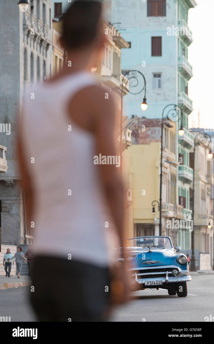 A boy watching a classic car driving along The Malecon (coast road) in Havana, Cuba Stock Photo