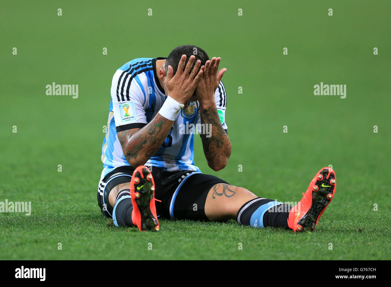 Argentina's Marcos Rojo shows his frustration as he sits dejected on the pitch during the FIFA World Cup Semi Final at the Arena de Sao Paulo, Sao Paulo, Brazil. Stock Photo
