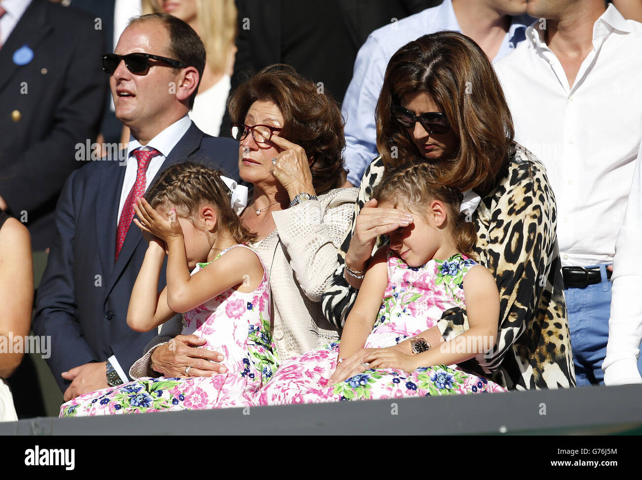 Charlene Riva and Myla Rose, daughters of Switzerland's Roger Federer, sit with their mother Mirka (right) and grandmother Lynette Federer as they show their emotions in the players box after watching their dad lose to Serbia's Novak Djokovic in the Mens singles final during day fourteen of the Wimbledon Championships at the All England Lawn Tennis and Croquet Club, Wimbledon. Stock Photo
