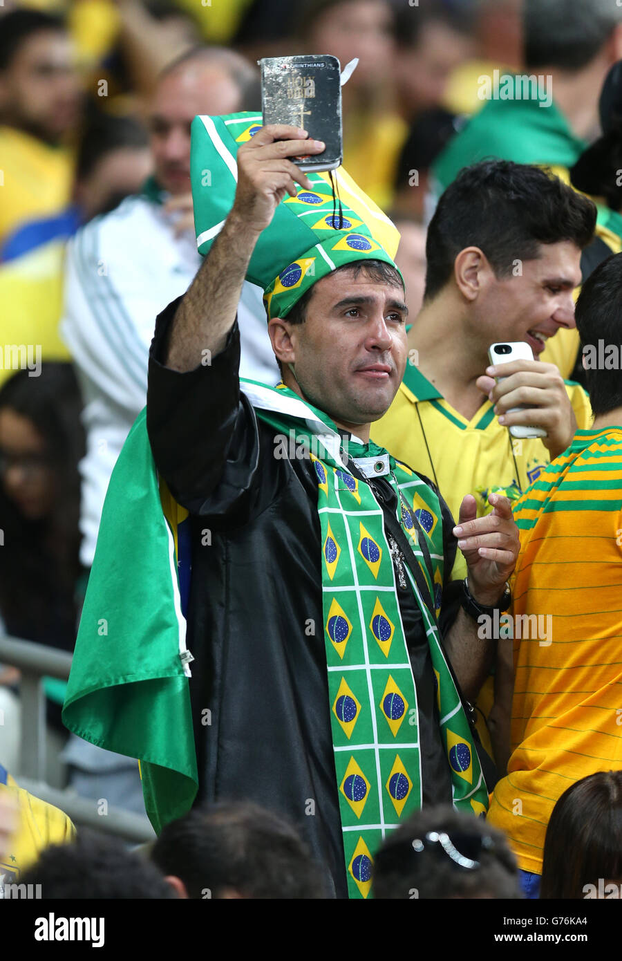 A Brazil fan holds up a bible in the stands during the FIFA World Cup Semi Final at Estadio Mineirao, Belo Horizonte, Brazil. Stock Photo