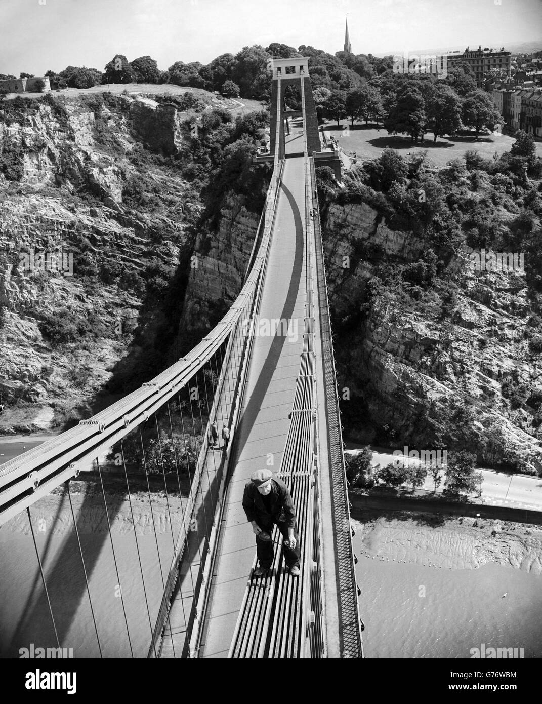 Perhaps the loftiest oiling job, and the coolest, in Britain is carried out by this workman, surefooted on the steep chains of the Clifton Suspension Bridge, 330 feet above the River Avon, Bristol. He inspects and oils the joints on the chains of the bridge. The bridge was designed by Isambard Kingdom and was completed in 1864. Stock Photo