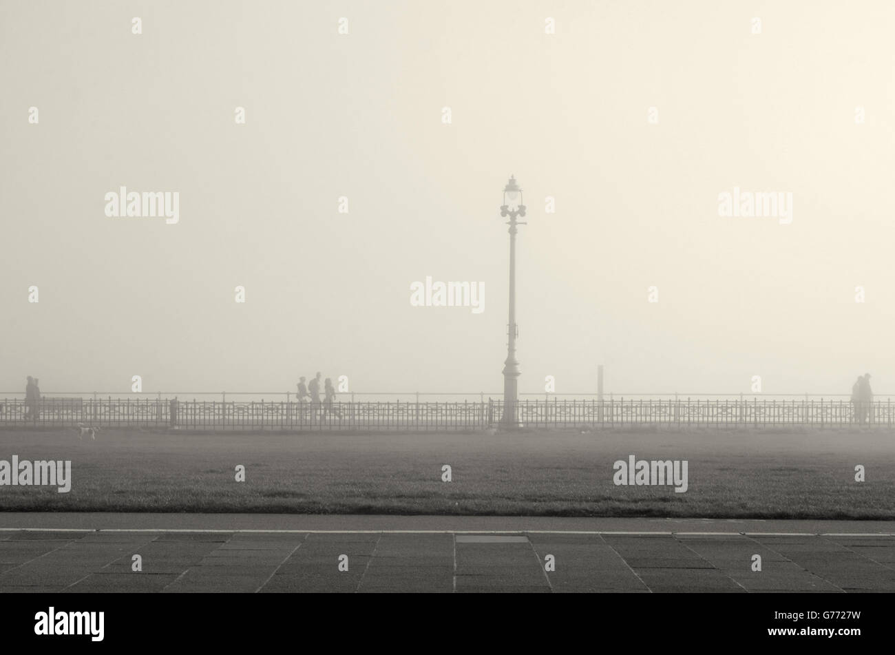 A bright but foggy morning on Hove seafront, ghostly silhouettes of holidaymakers and locals out for a morning stroll. Stock Photo