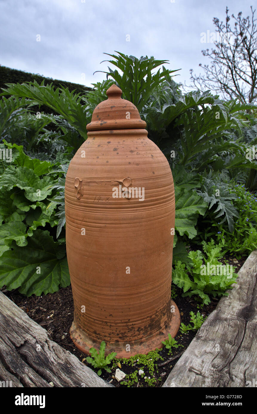 a clay forcing bell jar resting in place on the corner of a raised bed garden at the clergy house, Alfriston Stock Photo