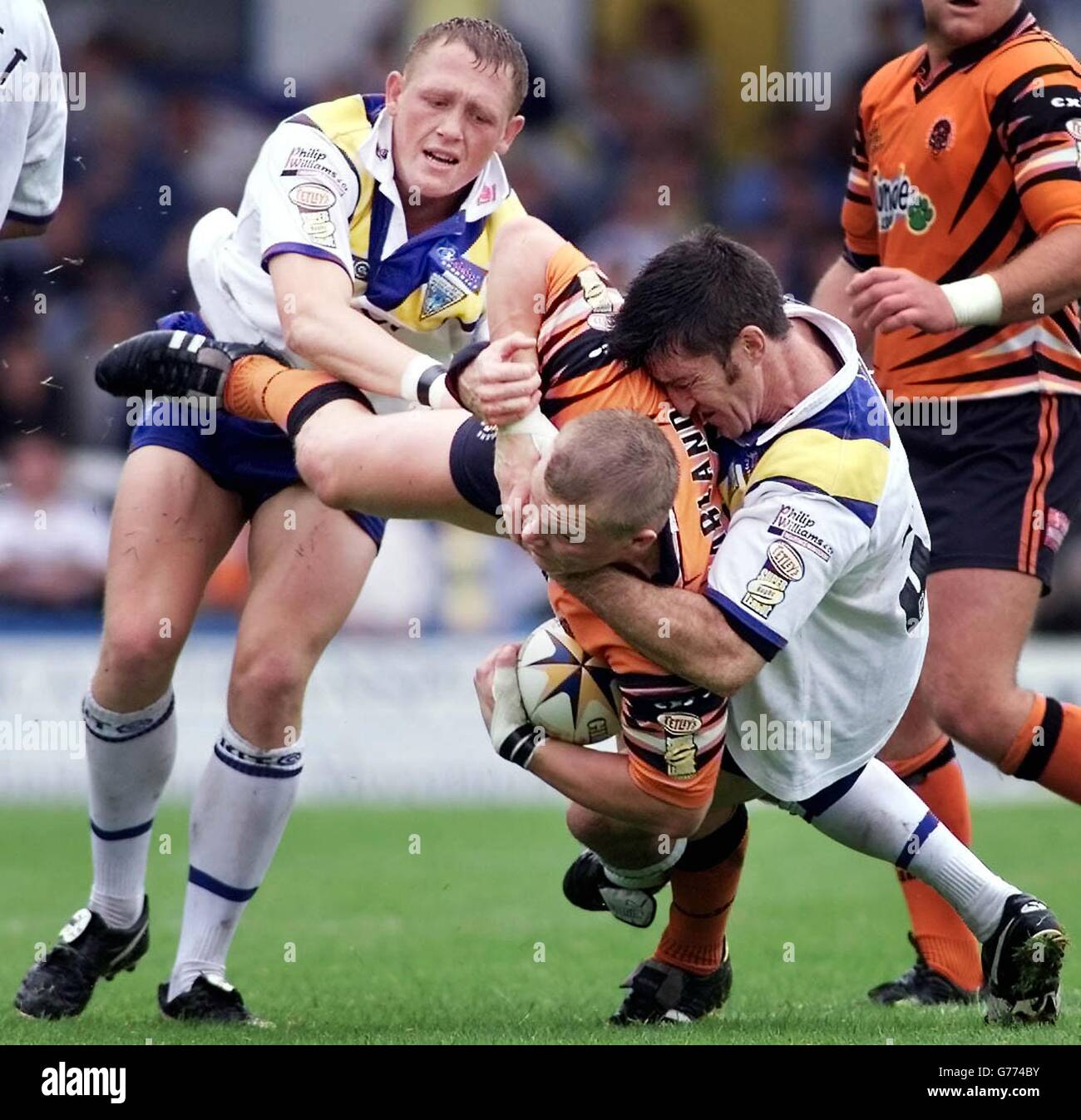 Castleford's Lee Harland is tackled by Warrington's Ben Westwood (left) and Nat Wood during their Tetley Bitter Super League game at Wilderspool, Warrington. Stock Photo