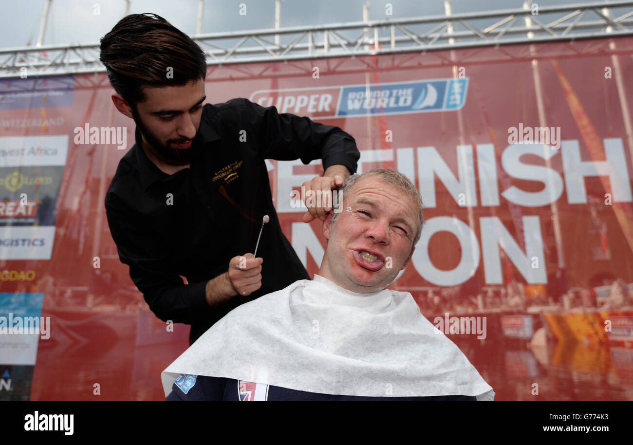 Great Britain team member and former England Rugby sevens player Ollie Phillips reacts as he has hair singed off his ears after having his beard shaven off after the Round the World Race Finish in London Stock Photo
