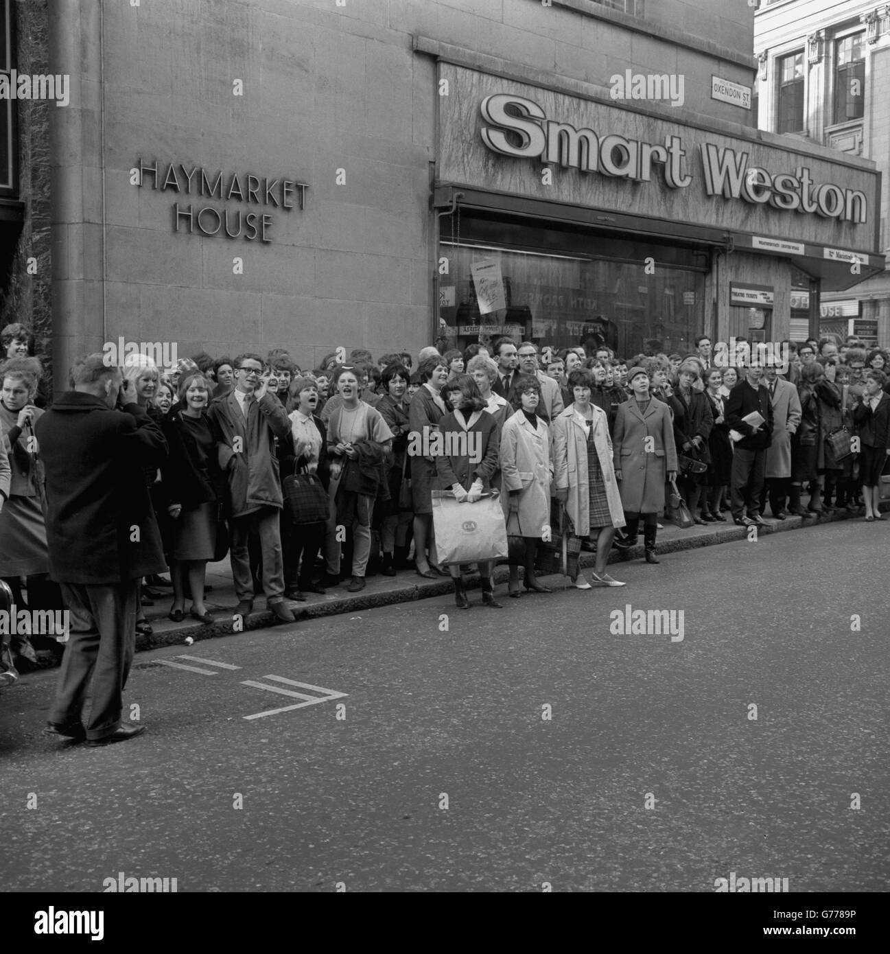 Beatles fans outside the Prince of Wales Theatre in London wait to catch a glimpse of their idols who were taking part in rehearsals for tonight's Royal Variety Performance. Stock Photo