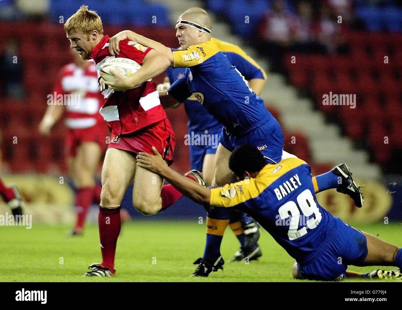 Wigan's David Hodgson is pulled back by Leeds's Matt Diskin and Ryan Bailey, during their Tetley Bitter Super League game at the JJB Stadium, Wigan. Stock Photo
