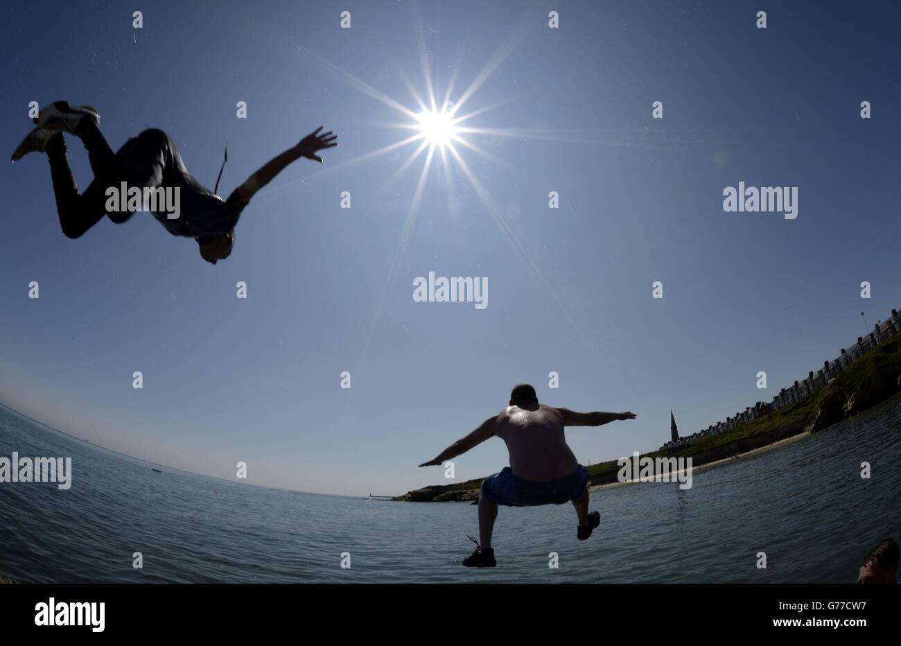 PLEASE NOTE: SHOT USING FISHEYE LENS People jump in the water at Cullercoats, North Tyneside as temperatures hit the high 20s. Stock Photo