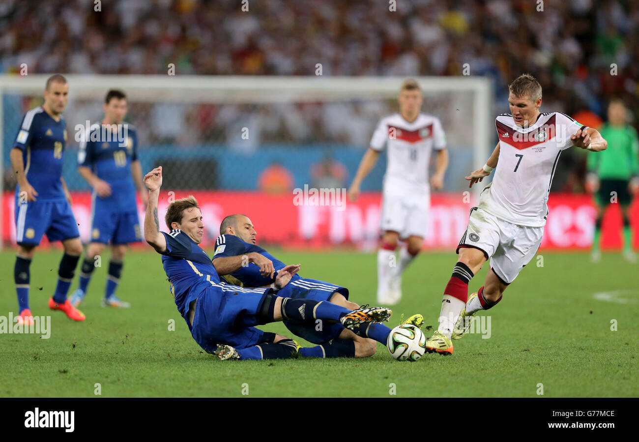 Soccer - FIFA World Cup 2014 - Final - Germany v Argentina - Estadio do Maracana. Germany's Bastian Schweinsteiger (right) is tackled by Argentina's Lucas Biglia (left) and Javier Mascherano Stock Photo