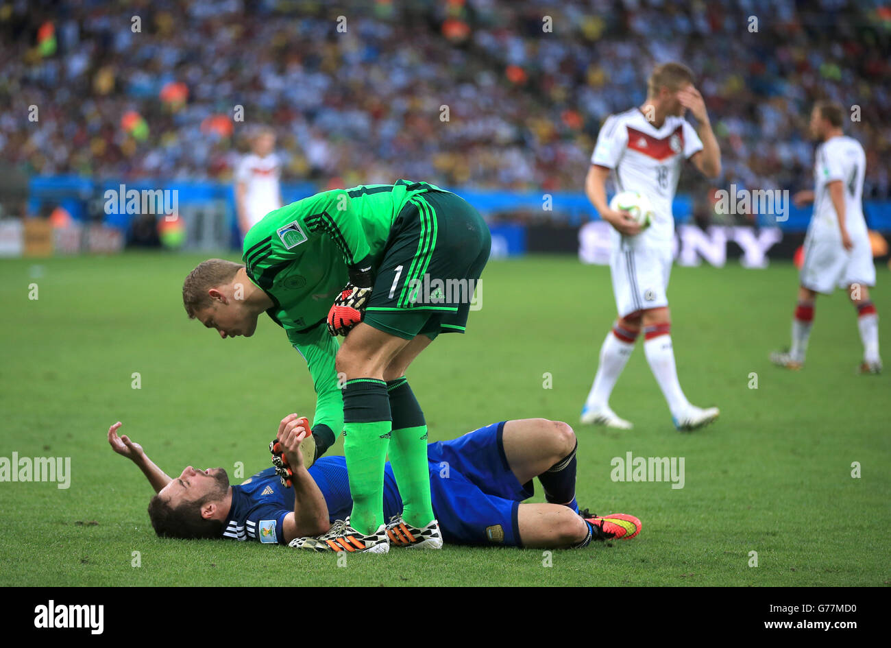 Germany goalkeeper Manuel Neuer checks on Argentina's Gonzalo Higuain (floor) after suffering a head injury Stock Photo