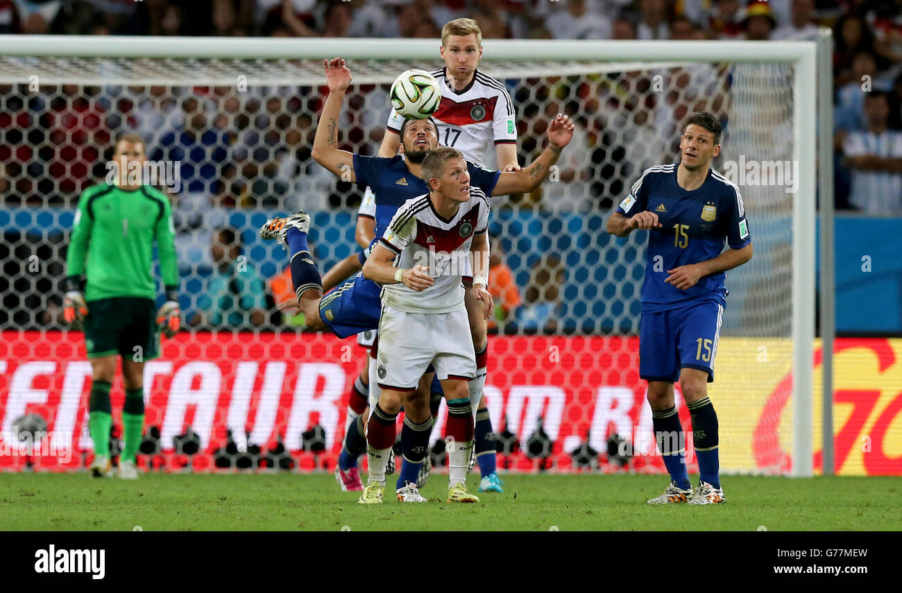 Soccer - FIFA World Cup 2014 - Final - Germany v Argentina - Estadio do Maracana. Germany's Per Mertesacker (centre, above) rises highest to head the ball clear of Argentina's Ezequiel Garay Stock Photo