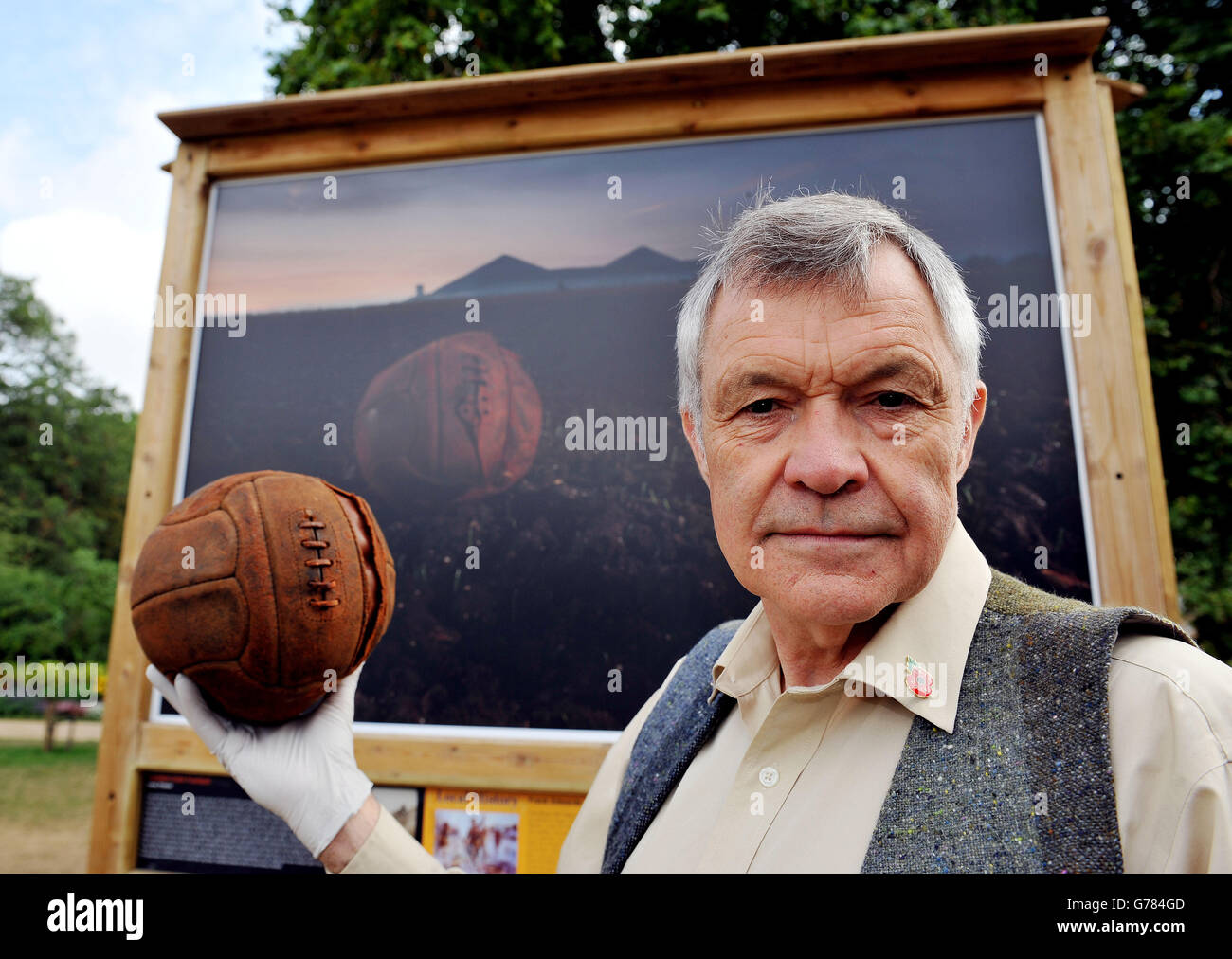 Photographer Michael St.Maur Sheil, holds the 'Loos Football' in front of his picture of the ball at Loos, which was kicked across no man's land by troops from the London Irish Regiment during the Battle of Loos in September 1915 as they advanced towards the enemy lines, during a preview of the Royal British Legion's Fields of Battle, Lands of Peace public street gallery in St James's Park central London, a series of present day photographs of WWI battlefields marking the centenary of the start of WWI. Stock Photo