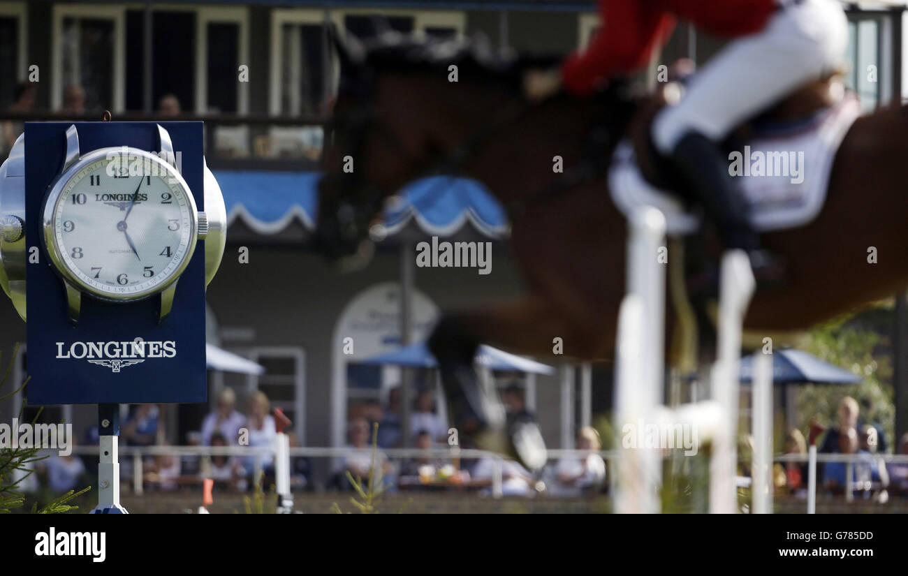 A horse jumps past the Longines clock in the Furusiyya FEI Nations Cup of Great Britain presented by Longines during day four of the Longines Royal International Horse Show at Hickstead. Stock Photo