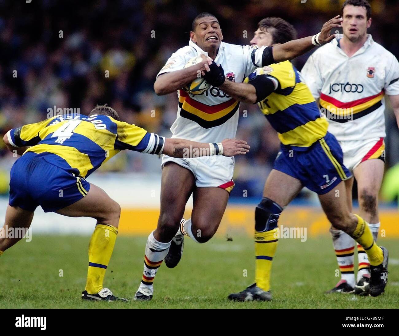 Bradford's Leon Pryce (centre) breaks through the tackles from Warrington's Ben Westwood (left) and Nat Wood during their Powergen Challenge Cup Fourth Round match at the Wilderspool stadium, Warrington. Stock Photo