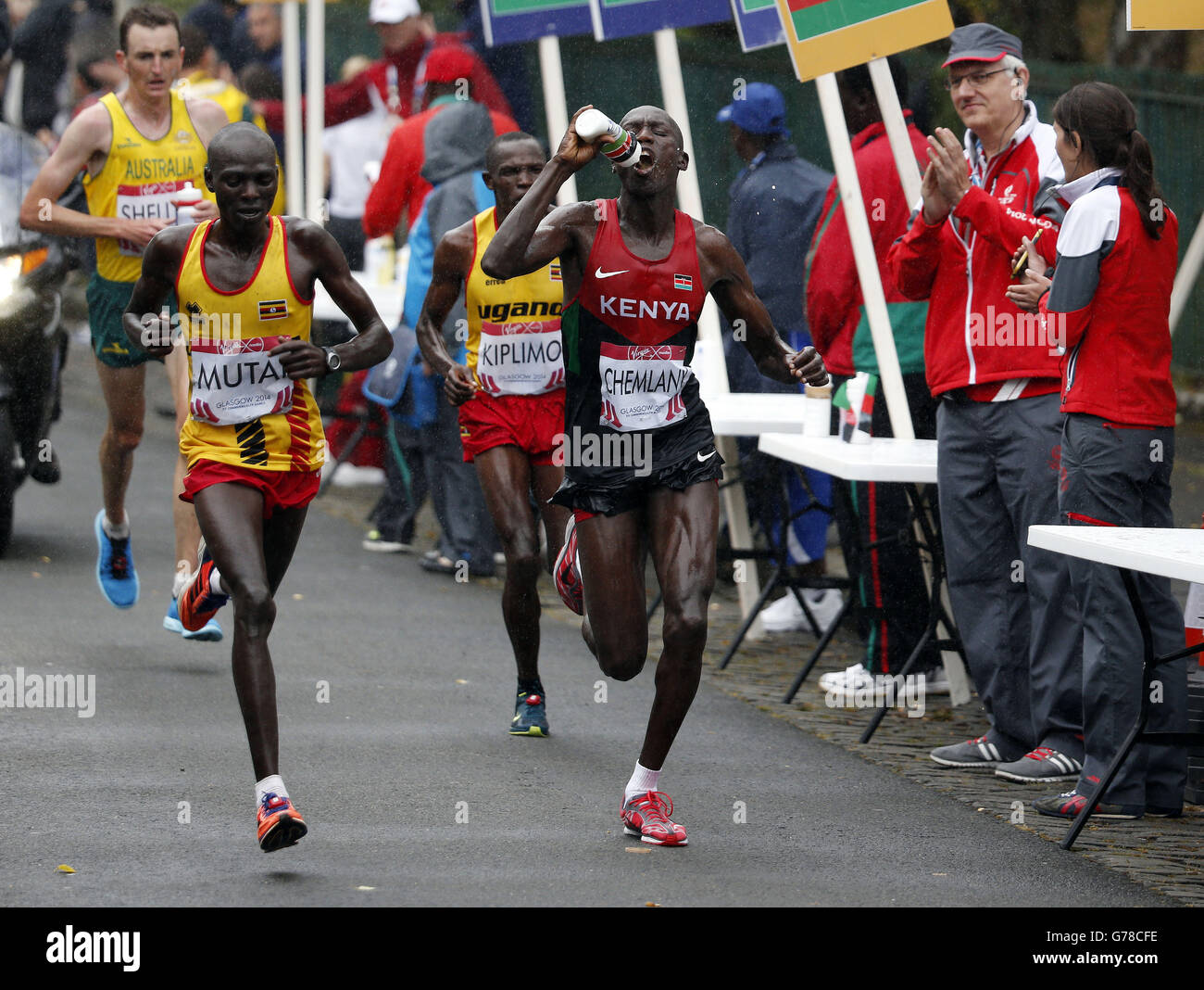 Kenya's Stephen Chemlany takes on water beside Uganda's Munyo Solomon Mutai (left) the men's marathon during the 2014 Commonwealth Games in Glasgow. Stock Photo