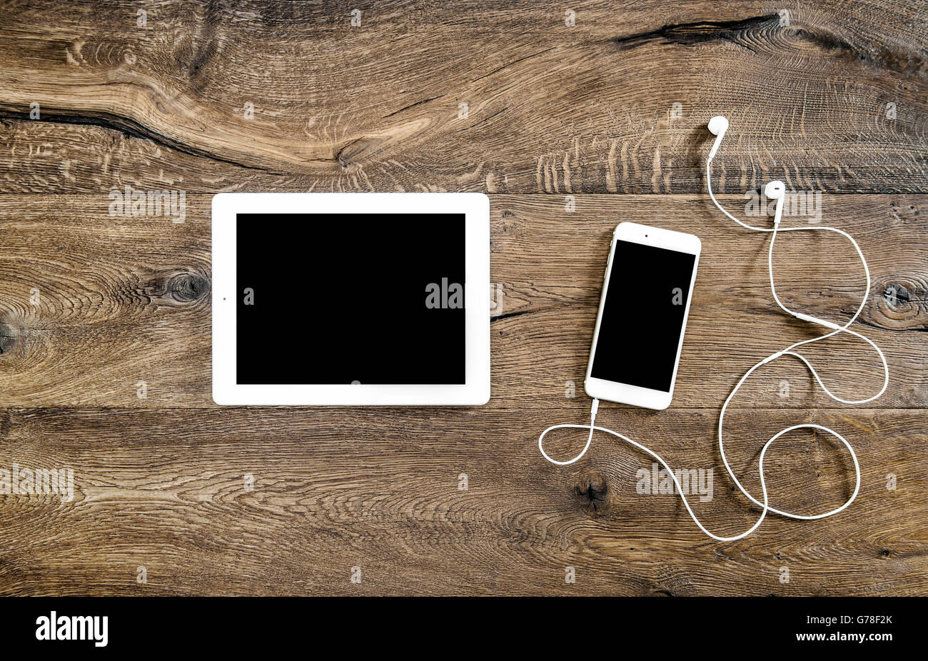 Phone with headphones and tablet pc on wooden background. Mockup screen electronic devices. Flat lay Stock Photo