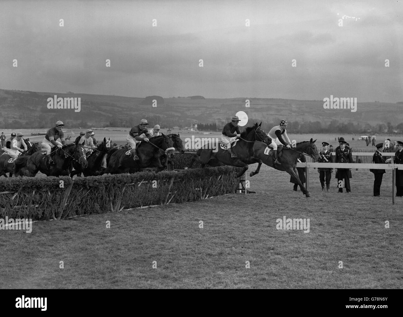 The field taking the first hurdle. In the lead are Mr H. T. Smith's 'Camugliano' (1, R. Emery) and Mr W. Clowes' 'Grand Morn' (30, Tim Molony). Stock Photo
