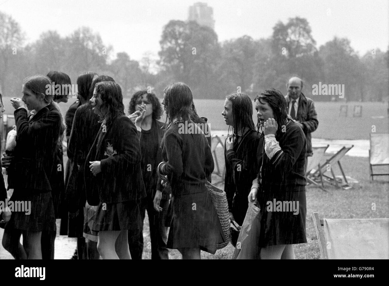 A group of schoolchildren head for shelter after a heavy downpour dampens their 'pupil power' demonstration at Speaker's Corner in Hyde Park. Children are protesting against caning, detention, uniforms and headmaster dictatorship. Stock Photo