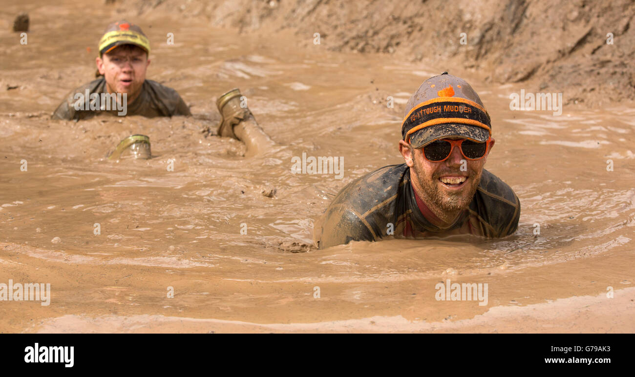 Mud bath taking a swim in a muddy puddle on the Tough Mudder obstacle course Drumlanrig Castle, Dumfries and Galloway, Scotland, UK Stock Photo