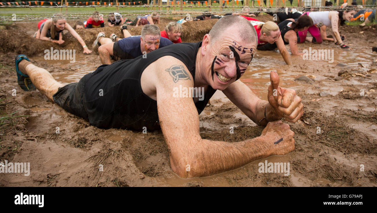 Tough Mudder man crawling through the Kiss of Mud obstacle Drumlanrig