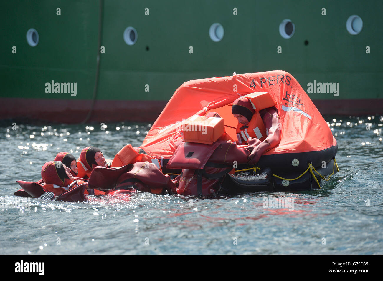 Emergency physicians wearing immersion suits mount a life raft next to ...