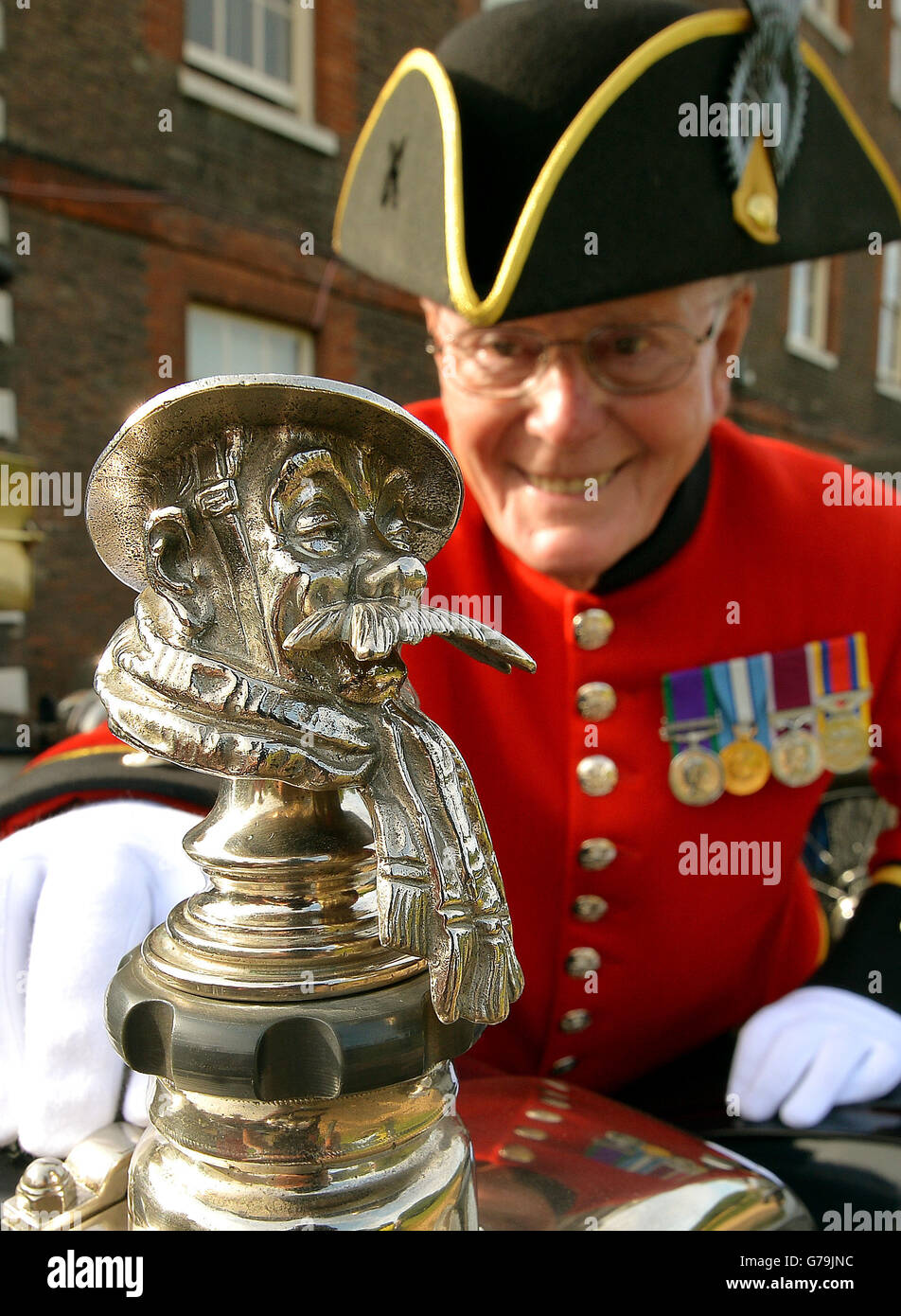 Sgt Patrick Cody, aged 77, admires the British Tommy Radiator cap of a vintage car ahead of their departure from the Royal Hospital Chelsea as part of the Great War Centenary Parade in central London. Stock Photo