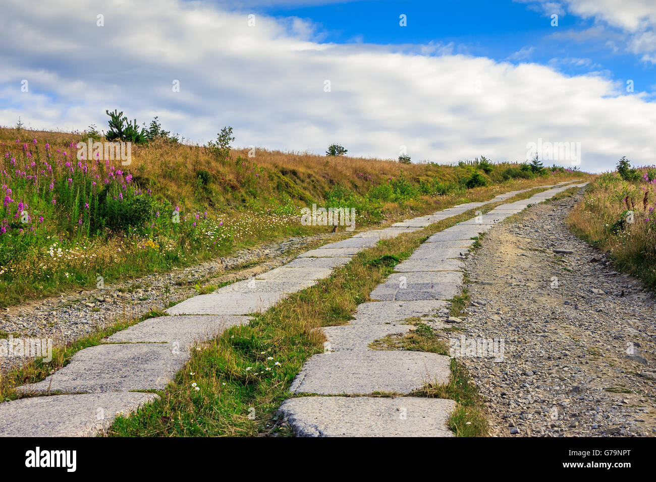 road of concrete slabs through the field turns uphill to the sky Stock ...
