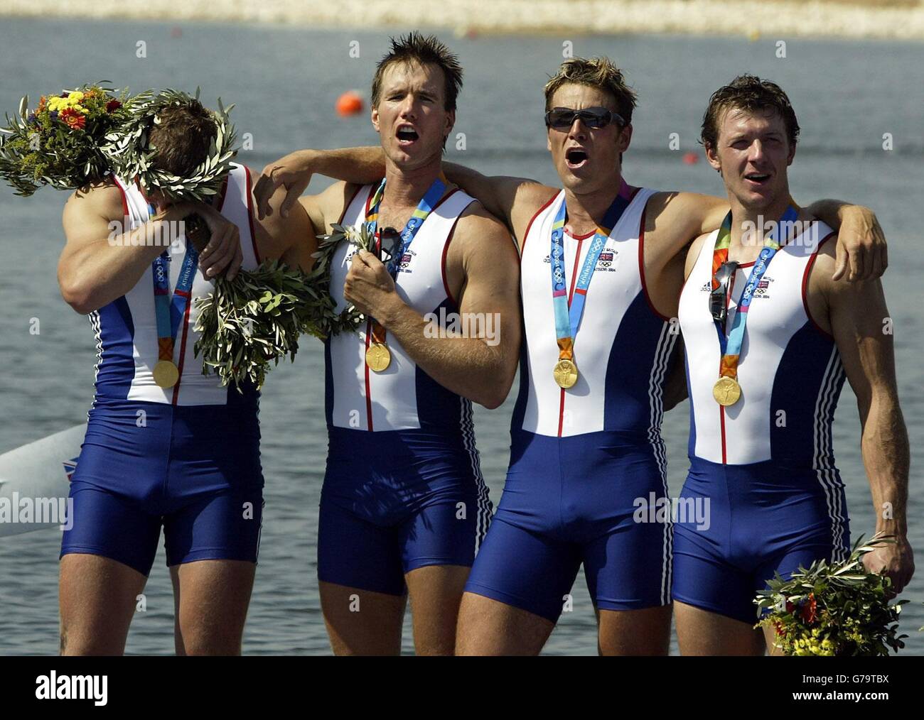 Great Britain's Matthew Pinsent (far left) reacts as his team mates (from left) Ed Coode, James Cracknell and Steve Williams sing the British national anthem following their win in the Men's Four rowing final during the 2004 Olympic Games at the Schinias Olympic Rowing Centre in Athens. Stock Photo