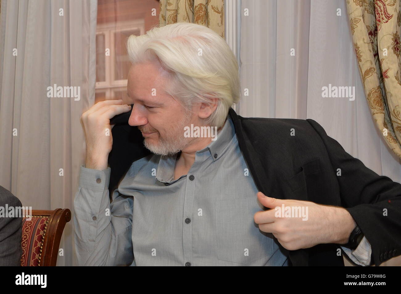 WikiLeaks founder Julian Assange puts on his jacket during a press conference inside the Ecuadorian Embassy in London, where Assange confirmed he 'will be leaving the embassy soon'. Stock Photo