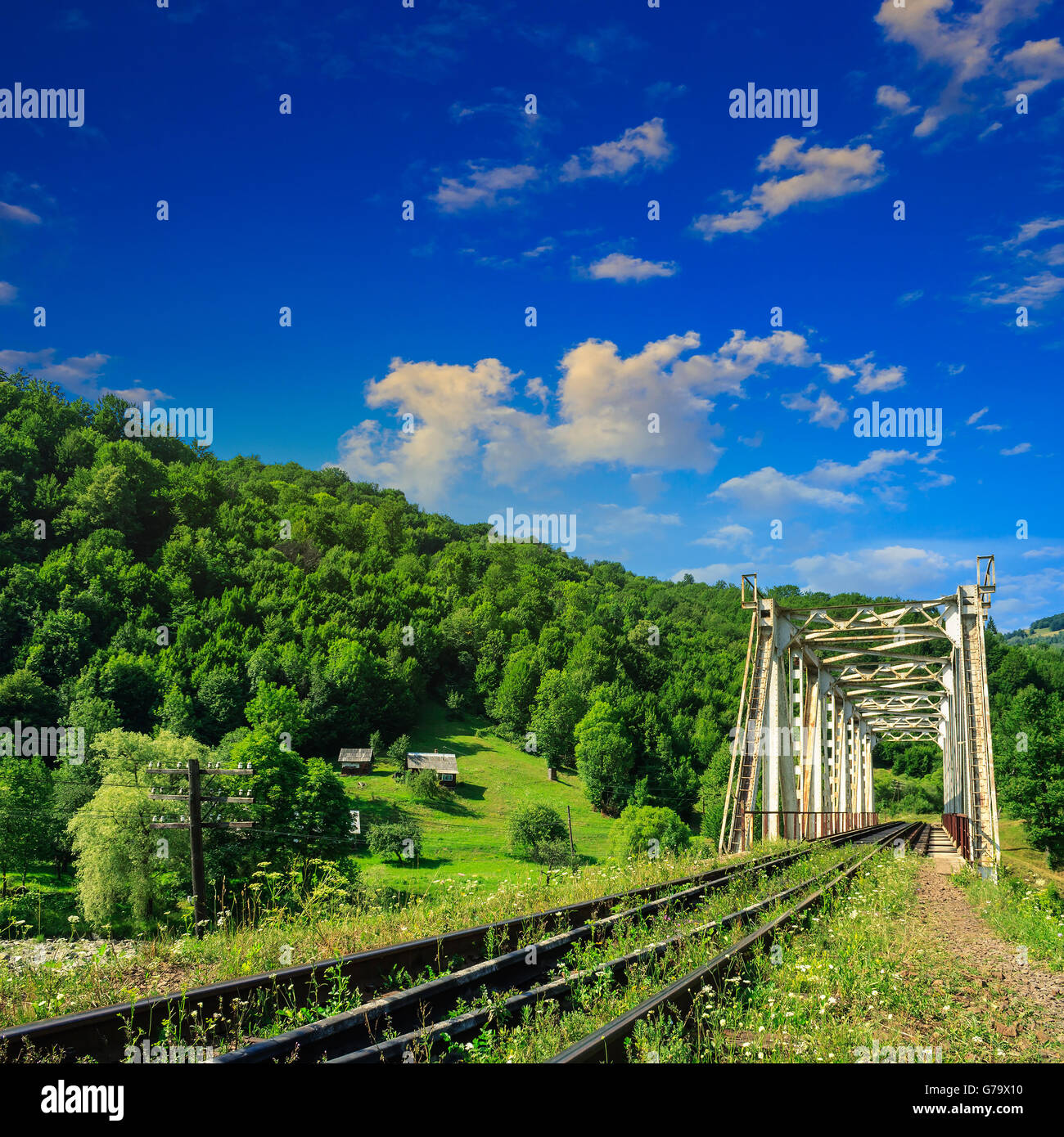 old railroad passes through the metal bridge in the mountain village Stock Photo