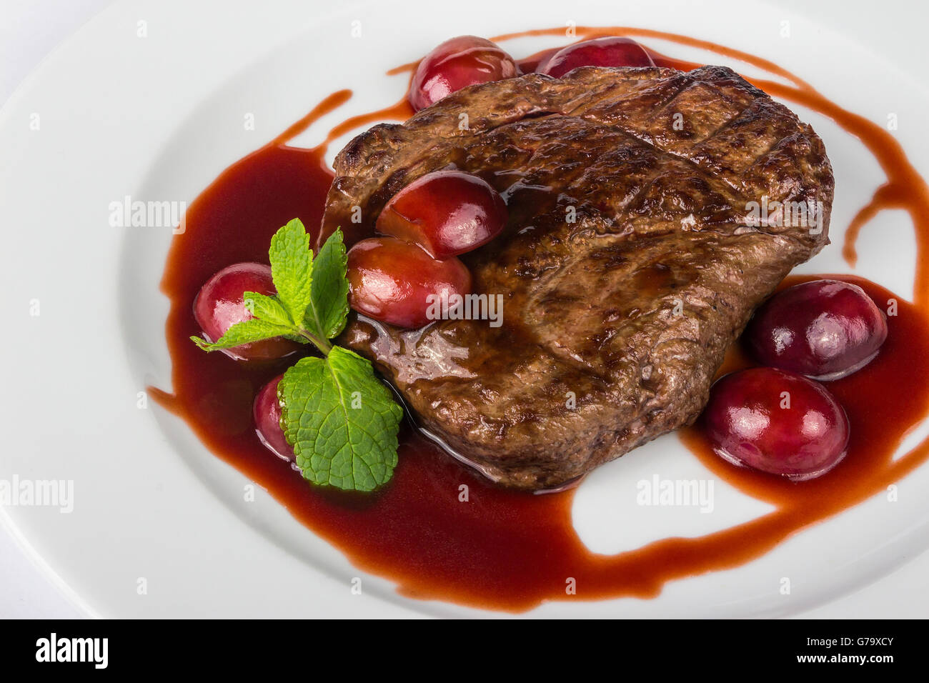 juicy grilled beef steak with plums in sauce with mint and summer taste