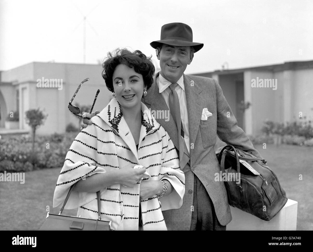 In pattern contrast coat, film star Elizabeth Taylor arrives with husband Michael Wilding at London Airport after their holiday in Rome. Stock Photo