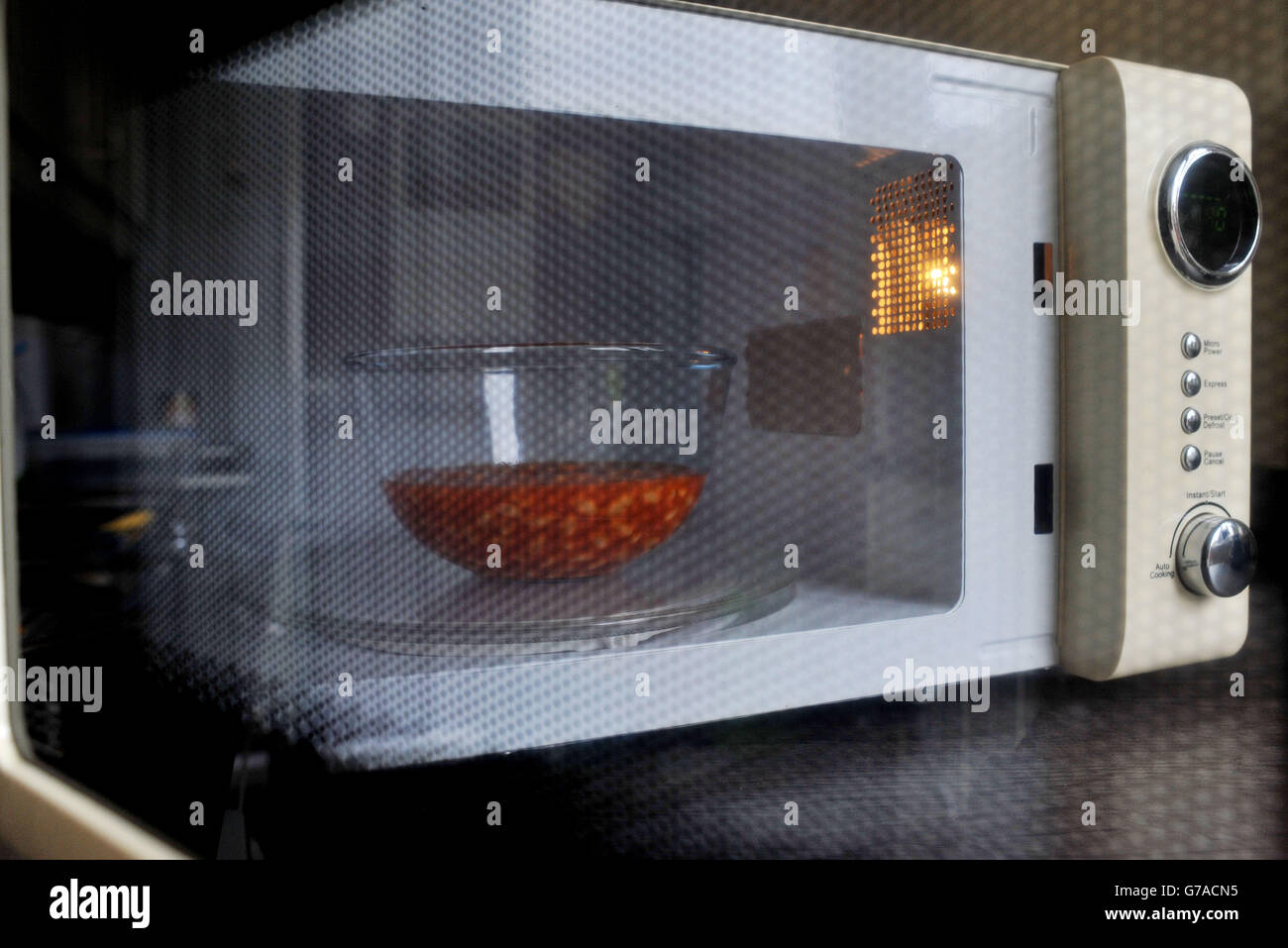 A view of a bowl of baked beans in a microwave cooker through the