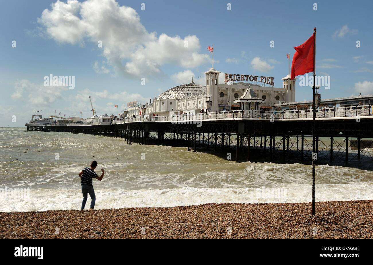 A young boy throws pebbles into the waves crashing on Brighton beach as the effects of ex-Hurricane Bertha are felt across England and Wales. Stock Photo