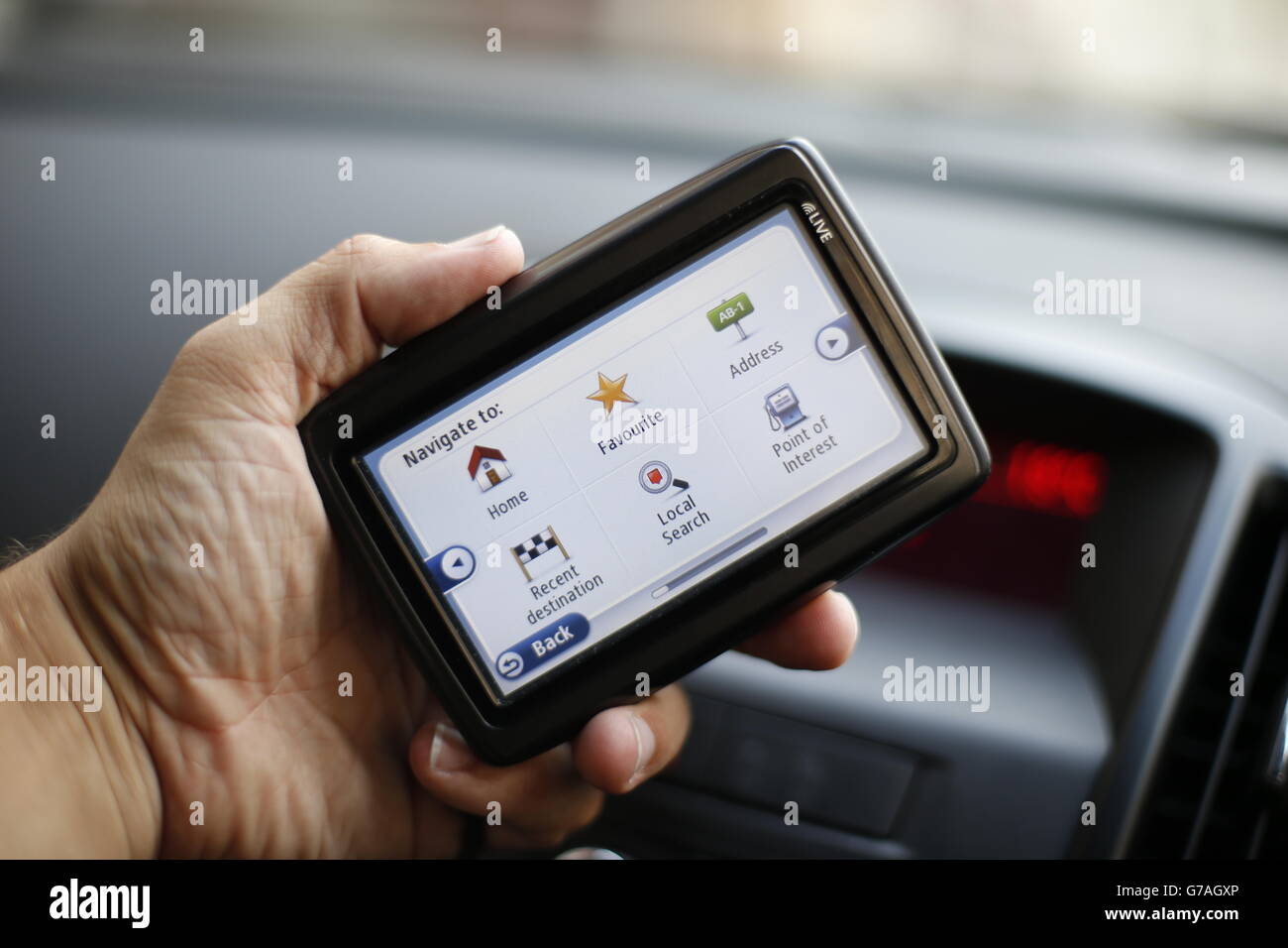 A man uses a satellite Navigator in his car. The sat nav system s a system of satellites that provide autonomous geo-spatial positioning with global coverage. It allows small electronic receivers to determine their location (longitude, latitude, and altitude ) to high precision (within a few metres) using time signals transmitted along a line of sight by radio from satellites. Stock Photo