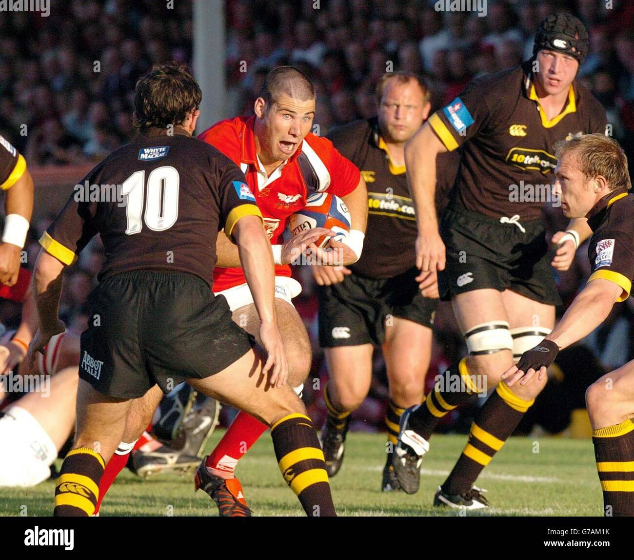 Llanelli's Mike Phillips charges at the Wasps' half back pair of James
