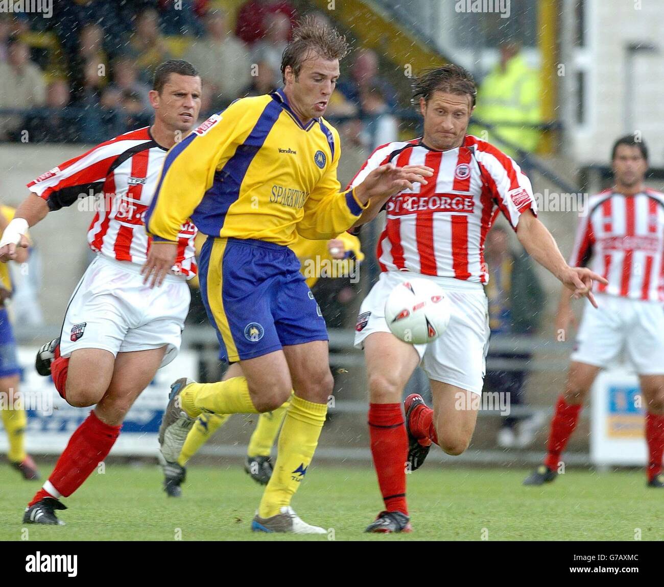 Bruno Meirelles of Torquay is challenged by Stewart Talbot & Chris Hargreaves of Brentford, during their Coca Cola League One match at Plainmoor, Torquay, Saturday, September 11, 2004. . Stock Photo