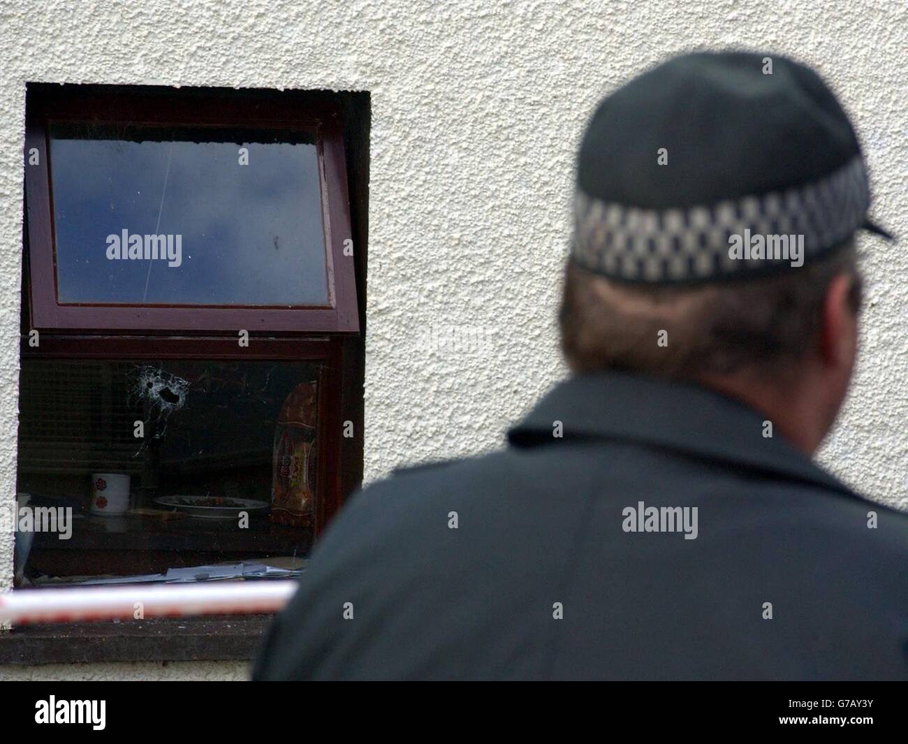 A police officer stands watch at the isolated cottage, outside Claudy where a farmer was found shot dead yesterday, possibly the victim of a feud over sheep-rustling. Patrick Devine's body was found with head wounds at his isolated farmhouse in Co Londonderry. Murder squad detectives believe the gunman opened fire through a kitchen window. Mr Devine, who was in his late 40s, lived alone in remote countryside, six miles from the village of Claudy. Stock Photo